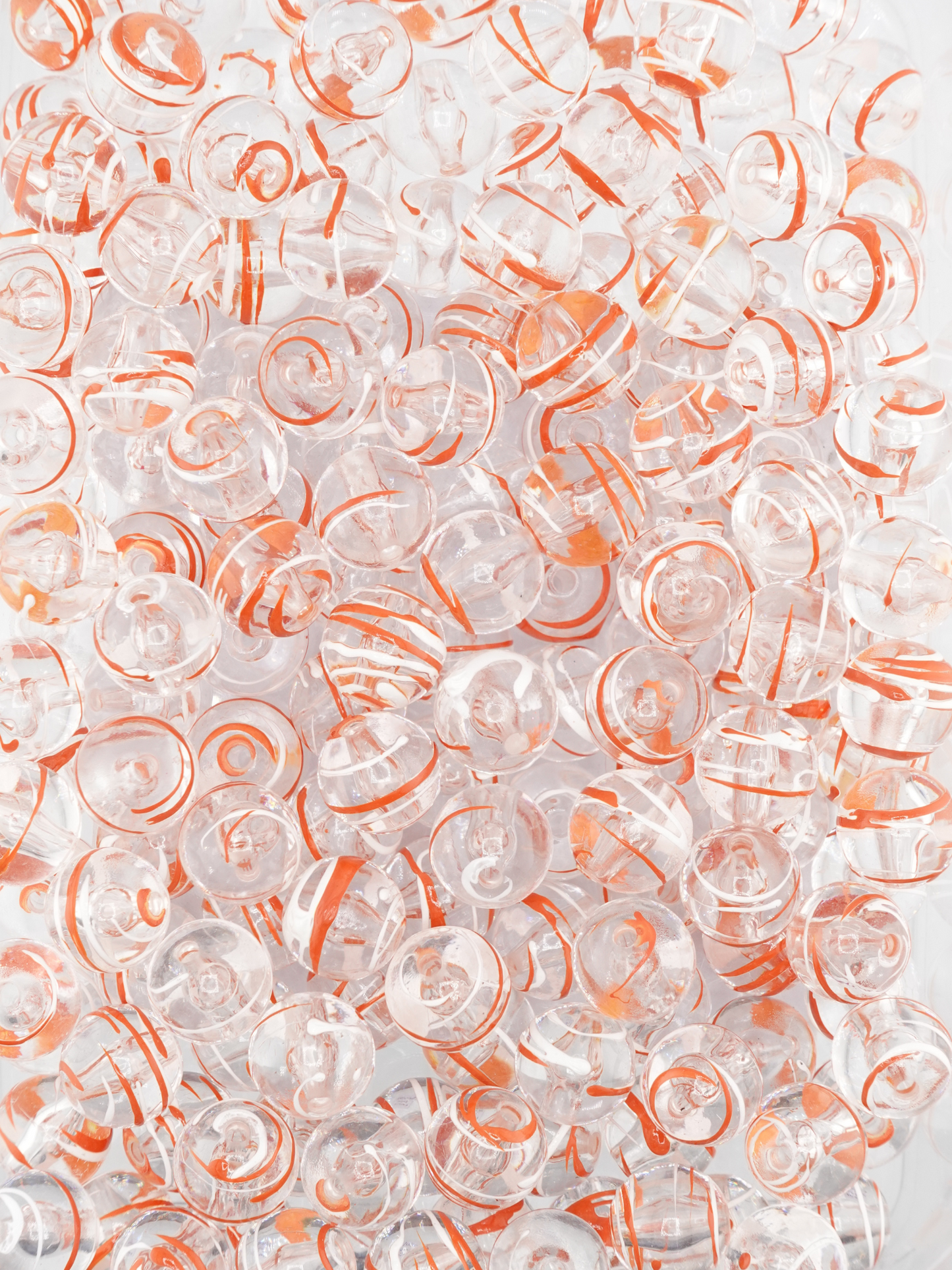 Collection of clear beads with a burnt orange and white paint stroke design