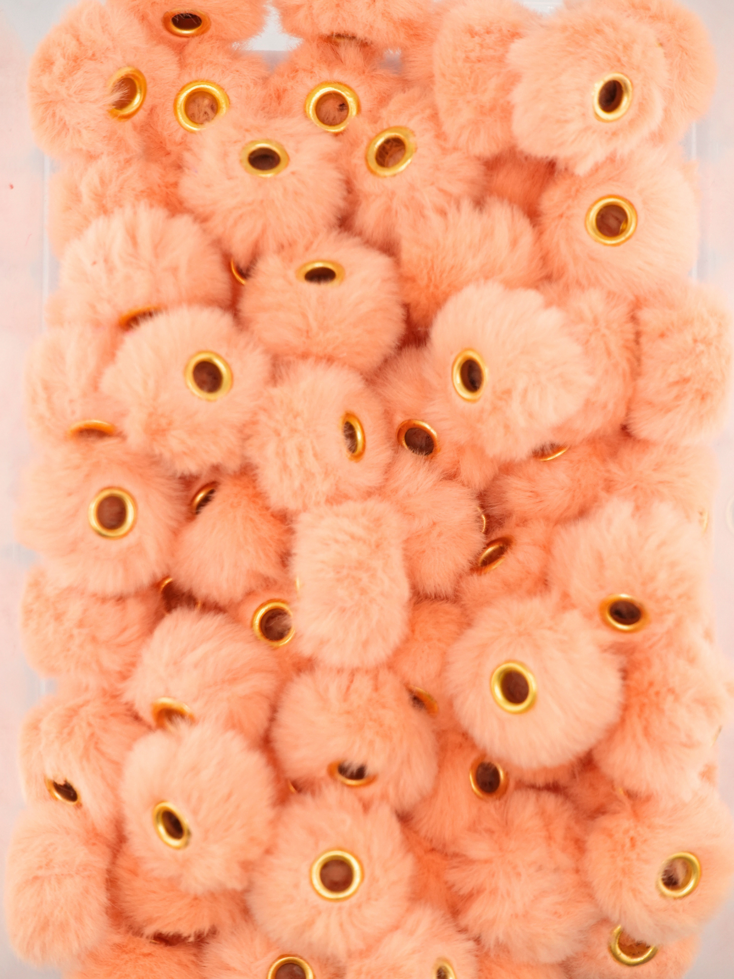 Collection of peach colored fuzzy pom pom spacers