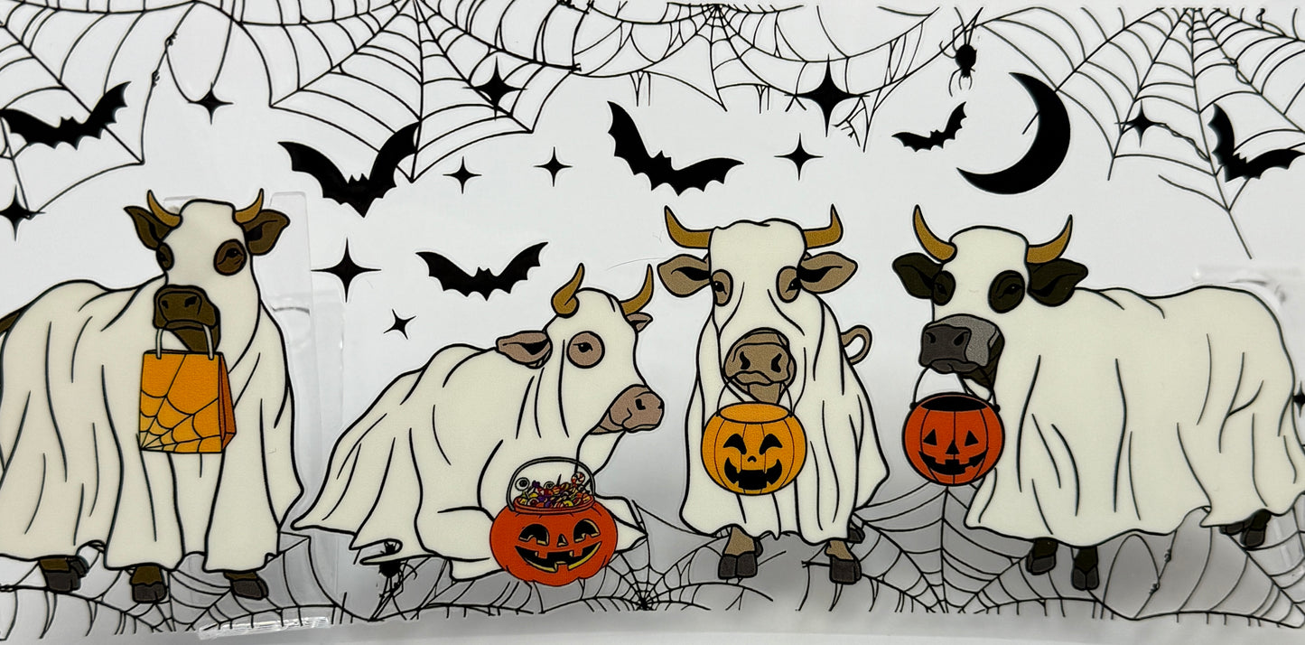 Four cows in Halloween costumes with pumpkins and ghosts on a spider web background.