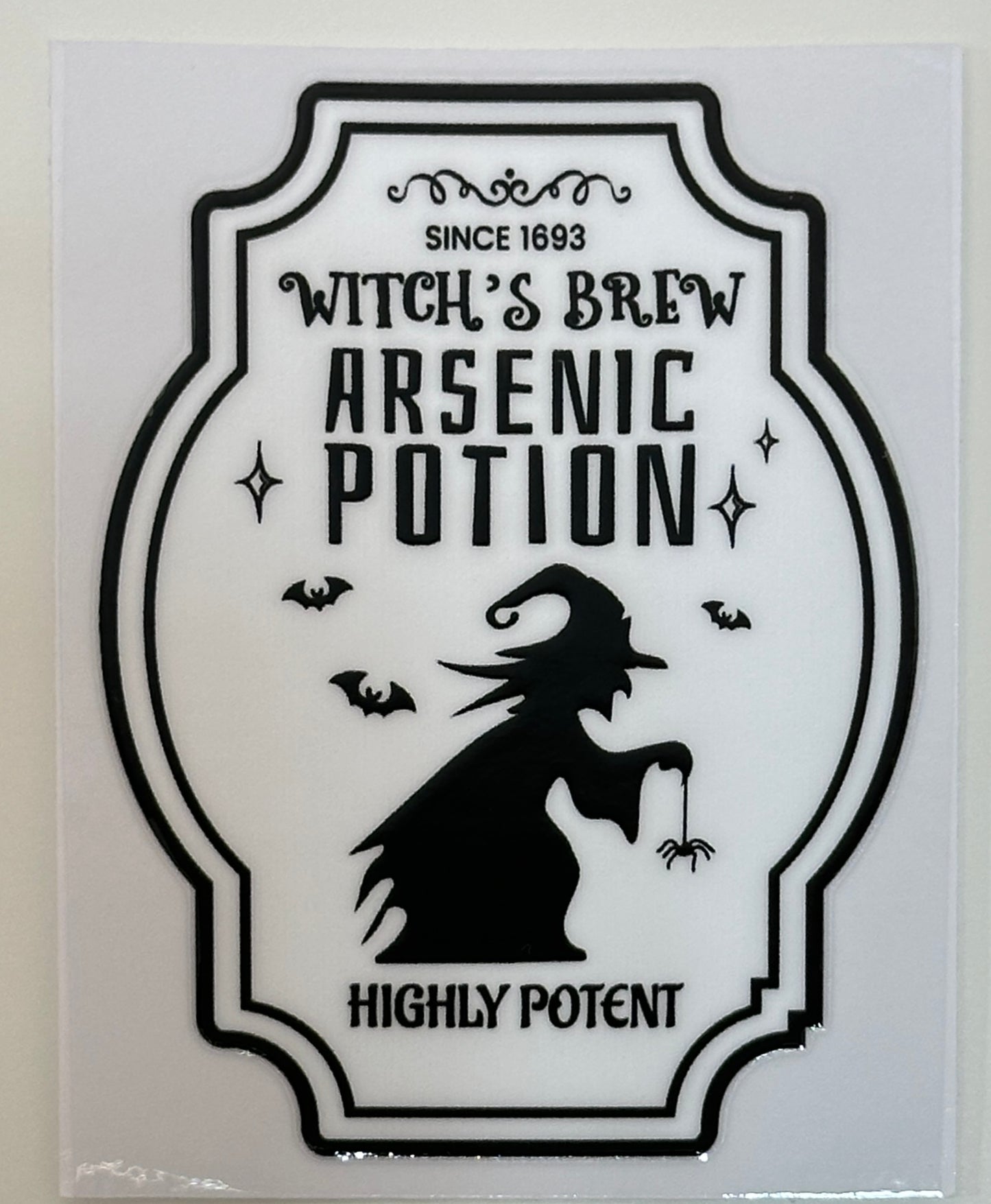 Decorative label for 'Witch's Brew Arsenic Potion' with a silhouette of a witch and text