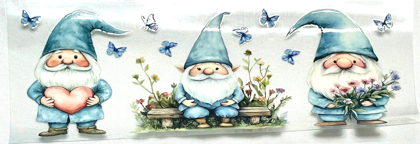 Three cartoon gnomes with blue hats and suits, holding a heart, flowers, and a basket of flowers, surrounded by butterflies