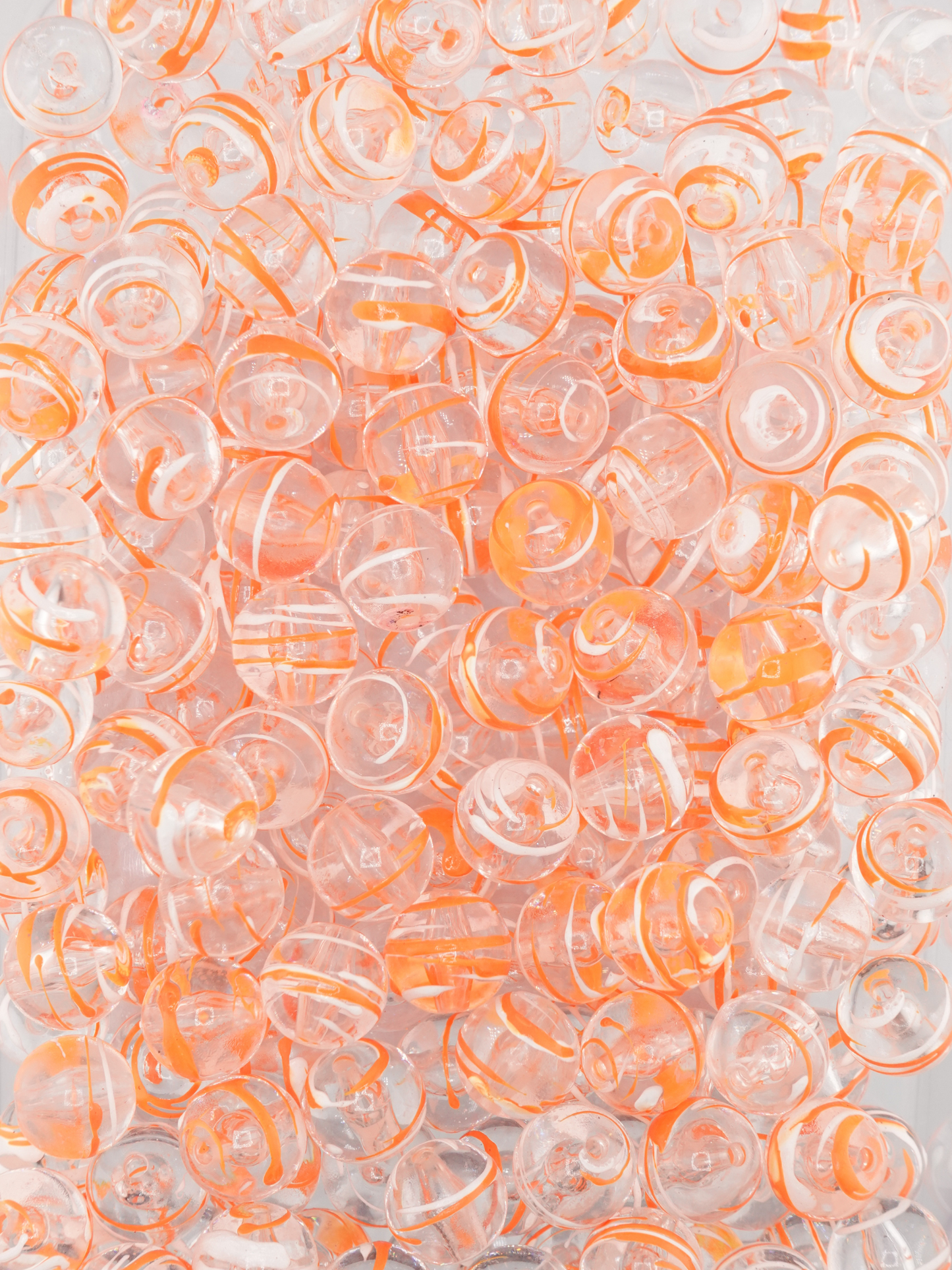 Collection of clear beads with a neon orange and white paint stroke design