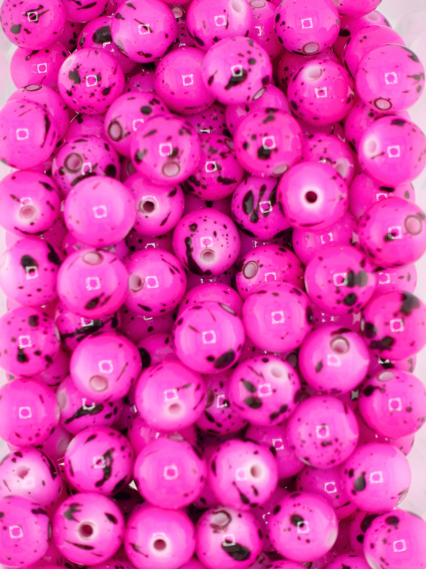 Collection of fuchsia beads featuring black paint splatters