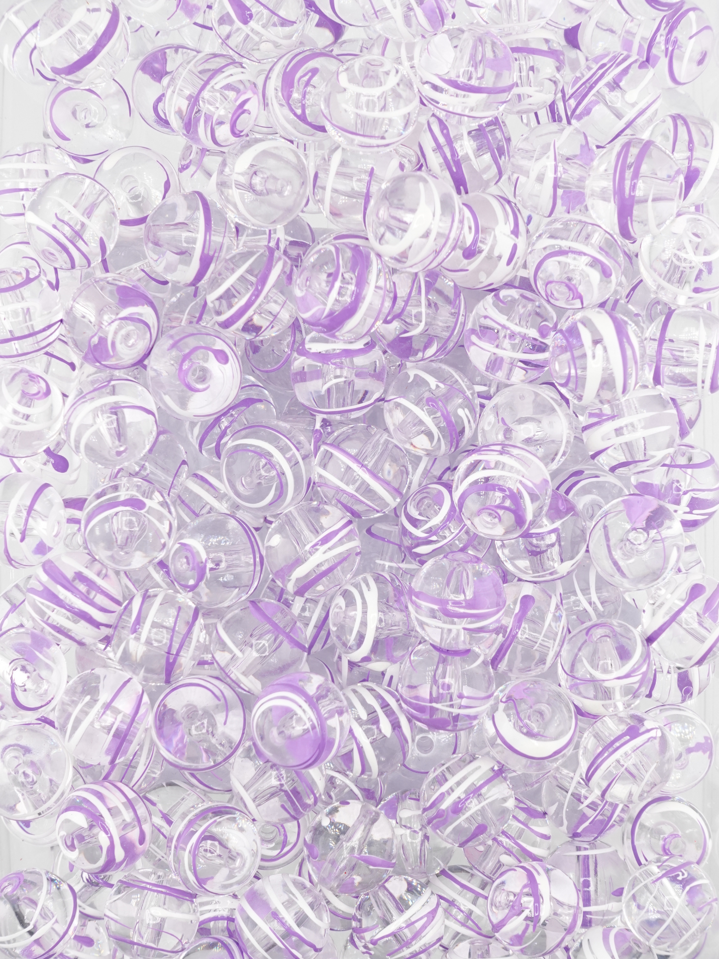 Collection of clear beads with a purple and white paint stroke design