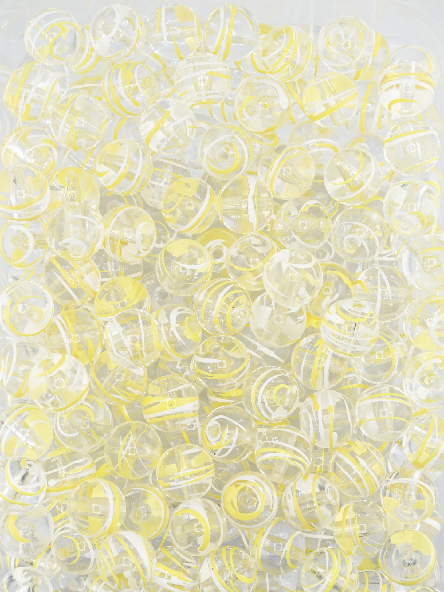 Collection of clear beads with a yellow and white paint stroke design