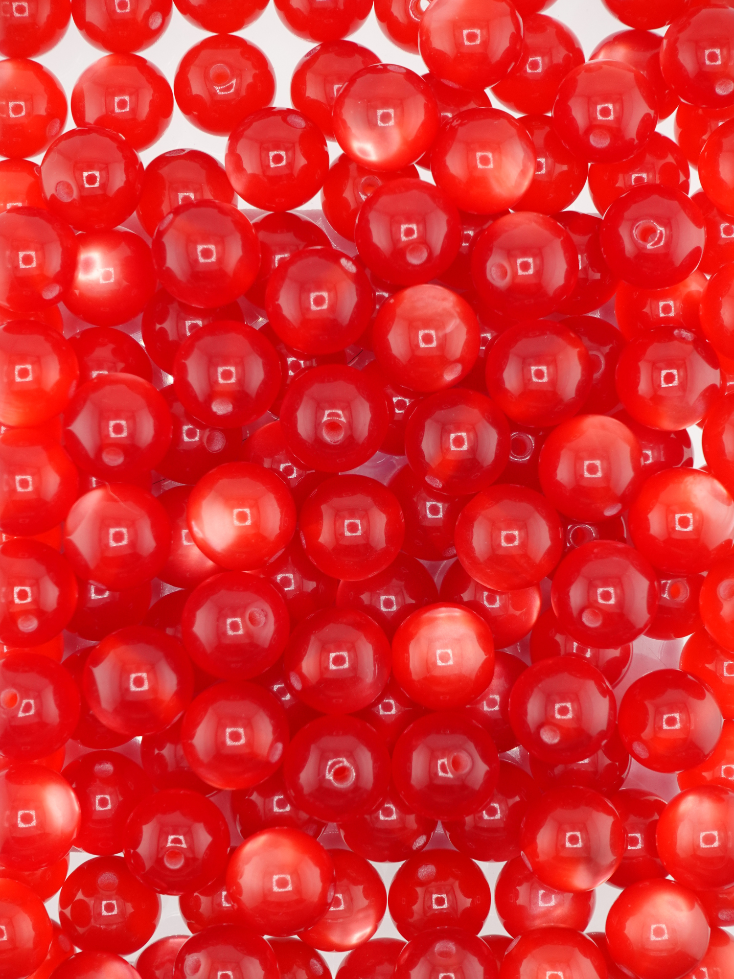 Collection of red colored beads with a cat eye shimmer