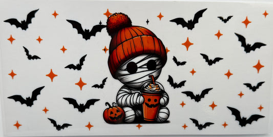 Cartoon mummy character with an orange beanie and pumpkin, surrounded by bats and stars 
