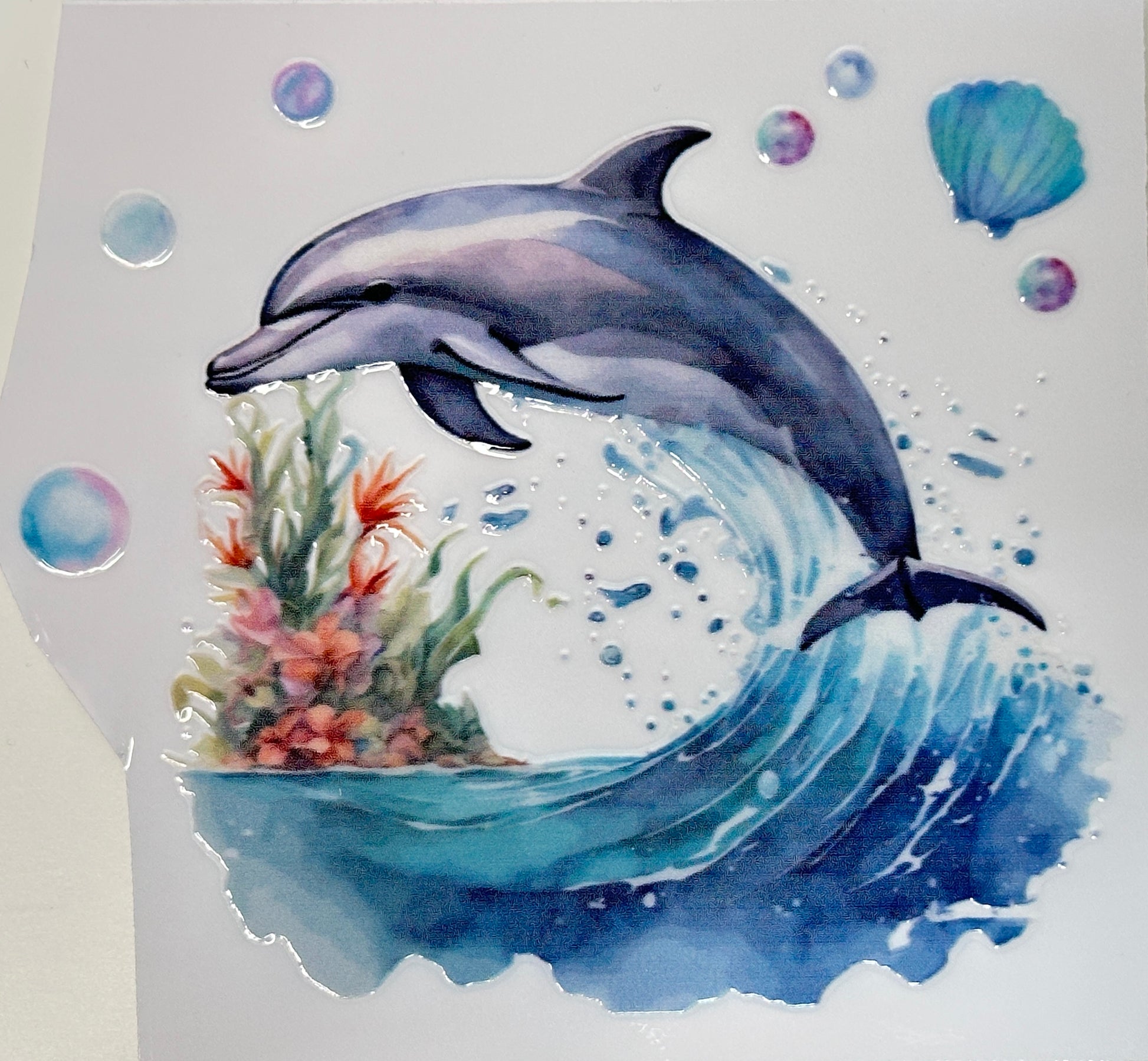Watercolor painting of a dolphin leaping out of water with coral and bubbles.