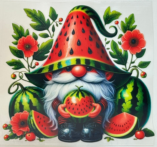 Gnome with watermelon hat and holding a watermelon surrounded by watermelons and flowers.