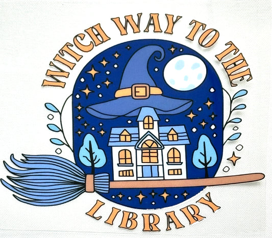 Illustration of a witch's hat with a house inside, surrounded by trees and a broomstick, with text 'Witch Way to the Library' on a white background.