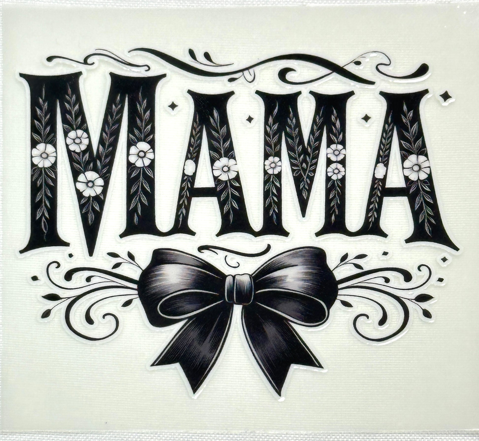 Decorative text 'MAMA' with floral elements and a bow on a white background