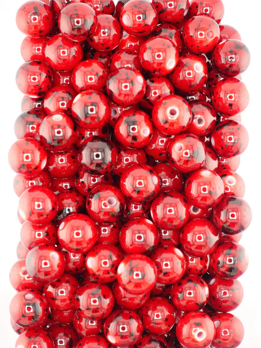 Collection of red beads featuring black paint splatters