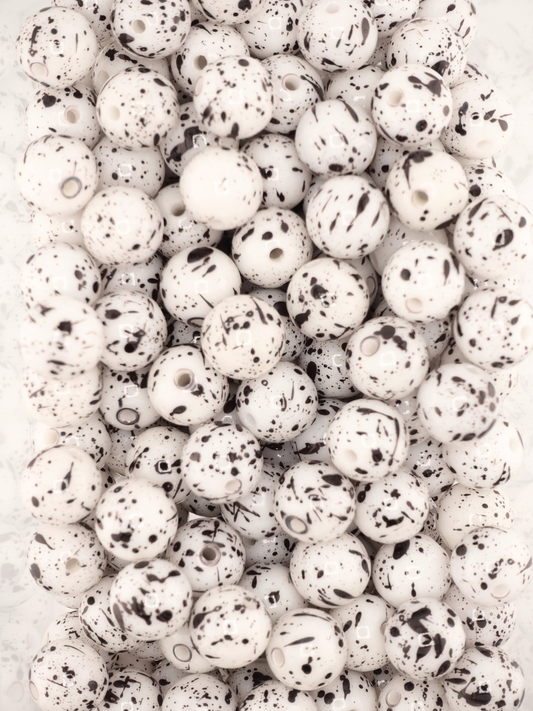Collection of white beads featuring black paint splatters