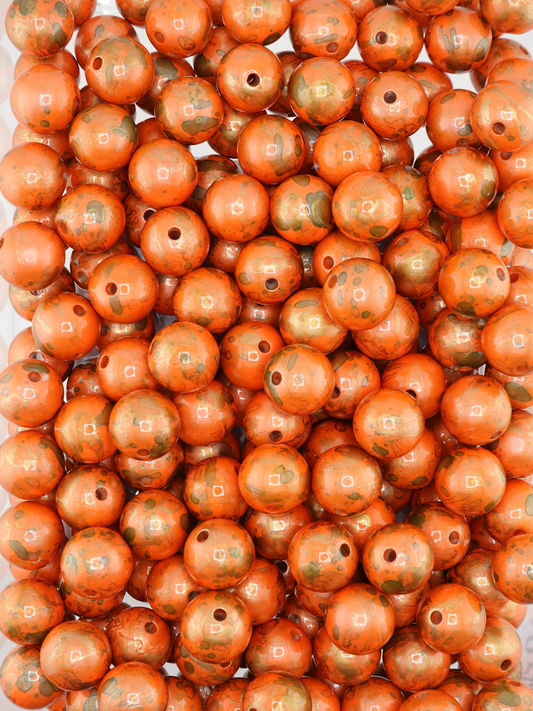 Collection of orange beads with a pearl finish and paint splatter design