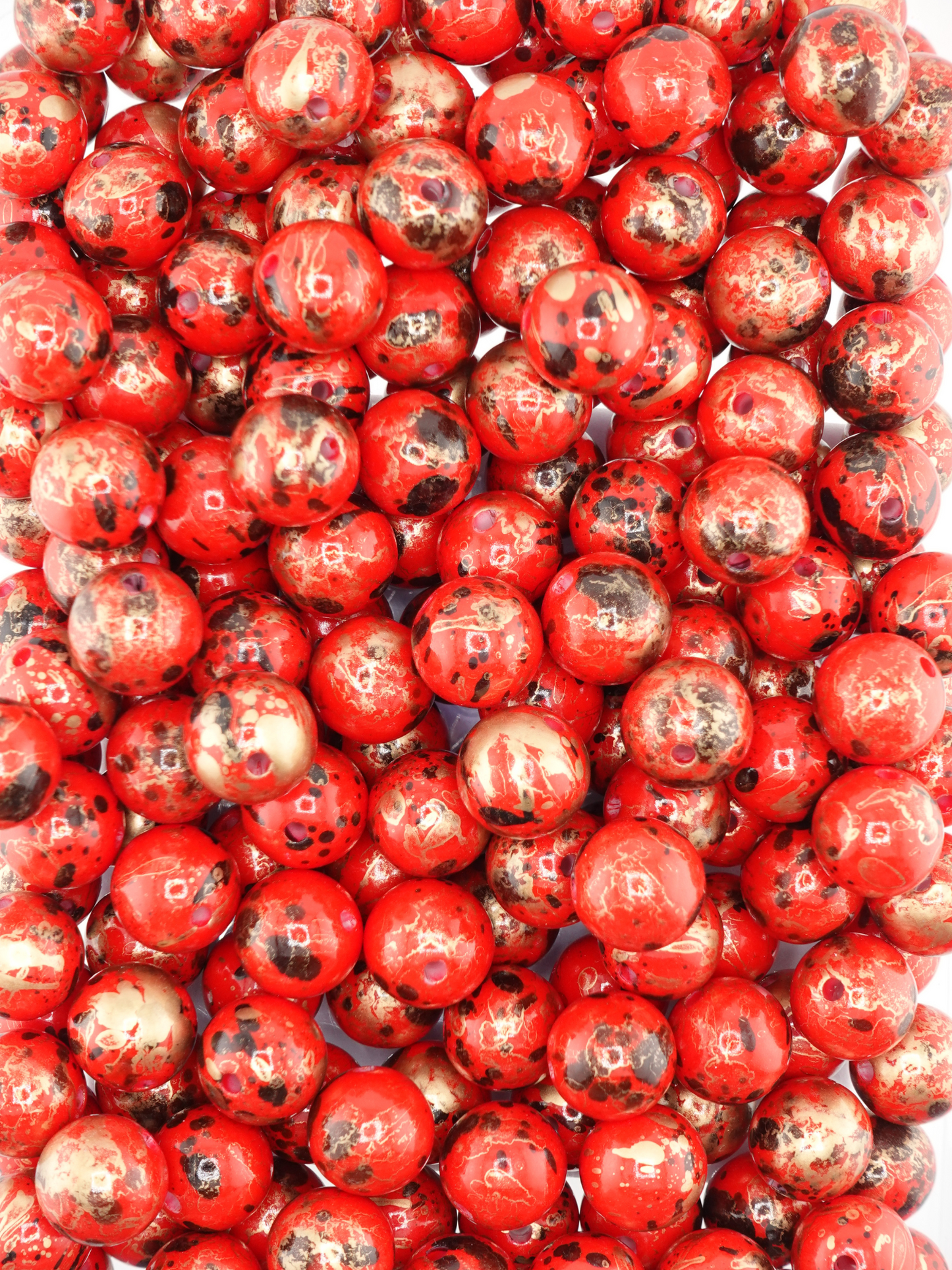 Collection of red beads with a pearl finish and paint splatter design