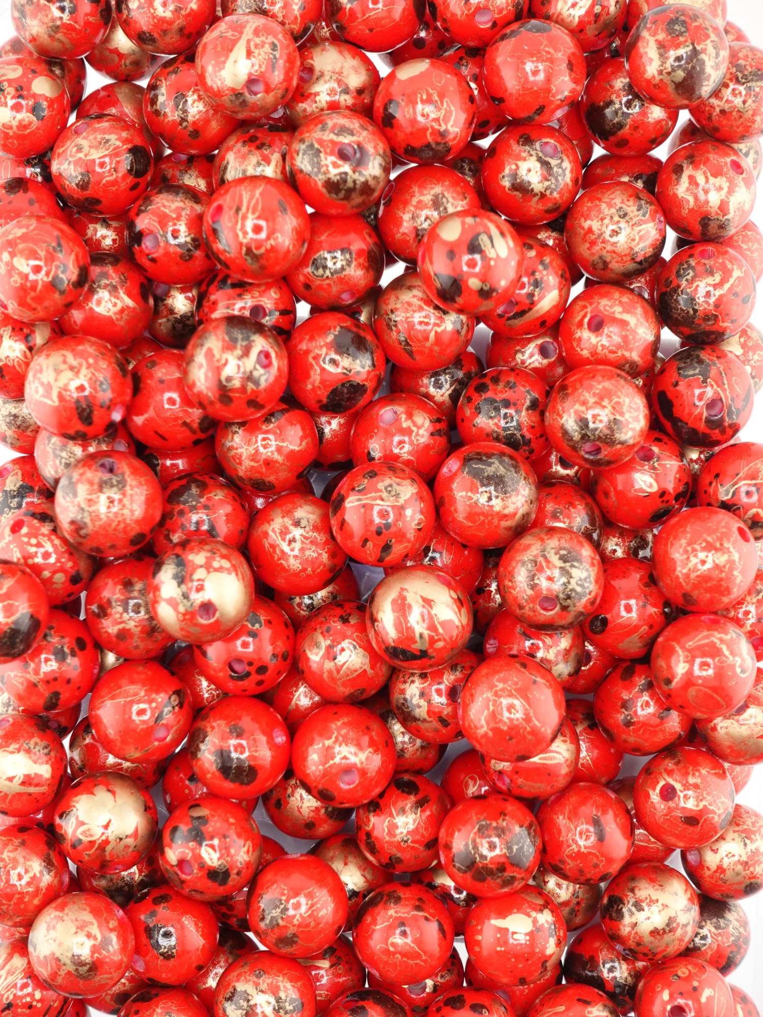 Collection of red beads with a pearl finish and paint splatter design