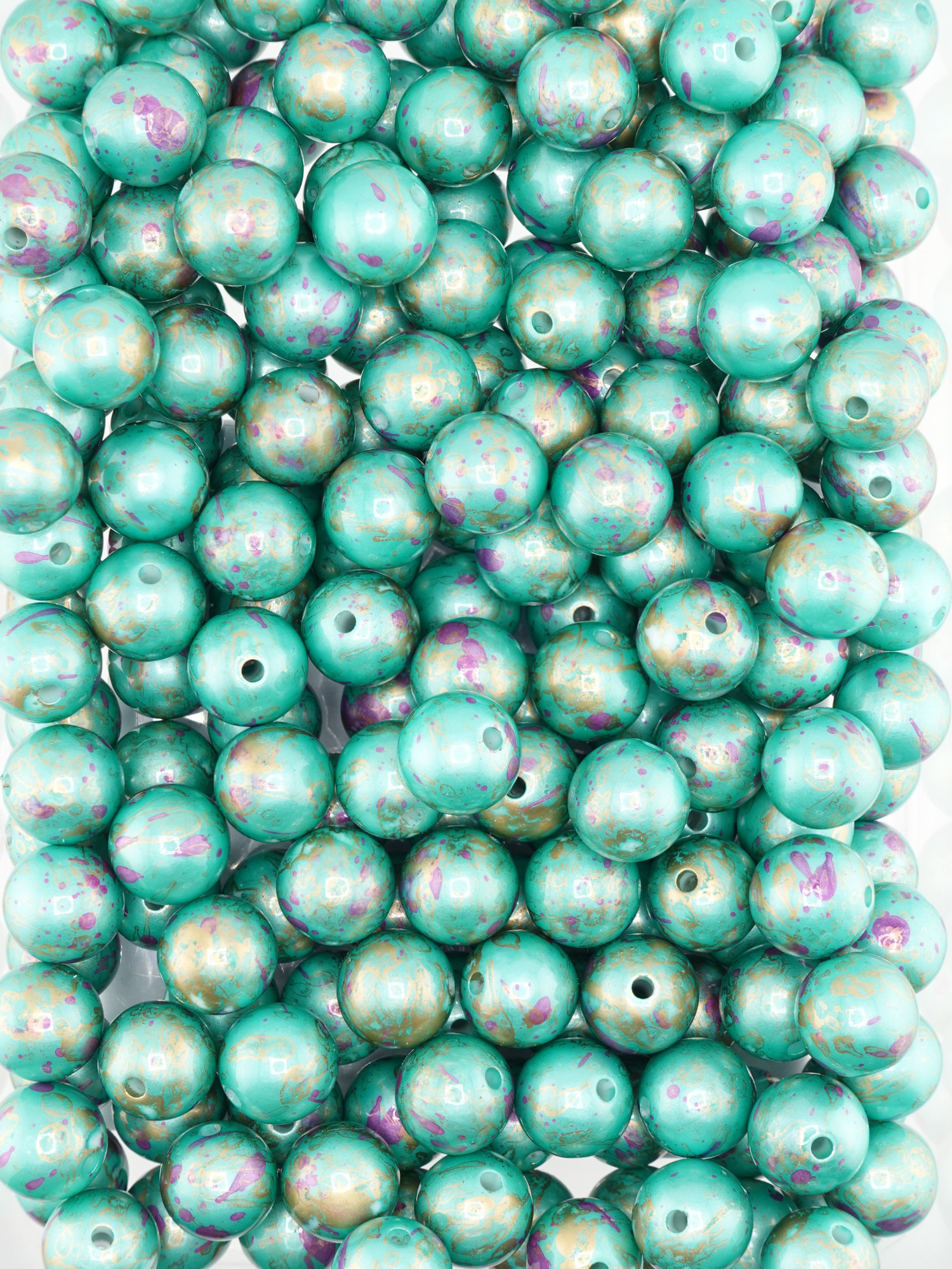 Collection of teal beads with a pearl finish and paint splatter design
